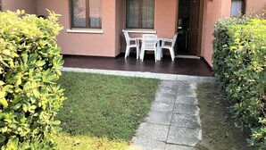 Un edificio con una veranda coperta, un piccolo tavolo con sedie e una porta che conduce all'interno.