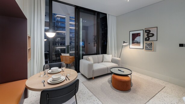 A modern hotel room with a dining area, a sofa, and a small table. - Urban Studio w Balcony Near Downtown and Canal (Dubai)