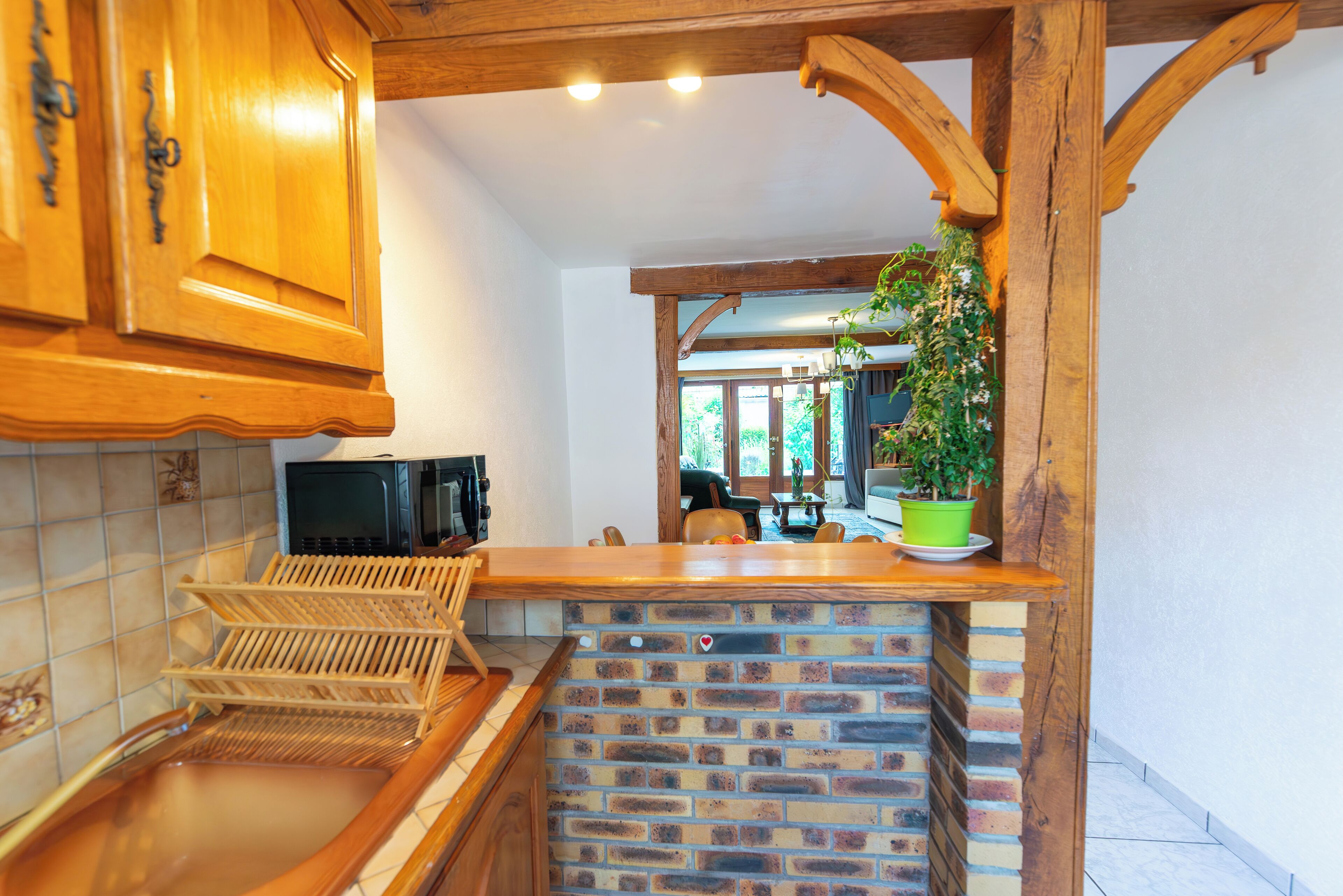 Une cuisine avec des armoires en bois, un mur de fond en briques et un plan de travail en bois.