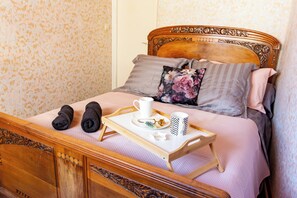 A neatly made bed with a floral pillow, a tray with a cup, a mug, and a pair of towels. - La Rosée - 2-room family apartment, Wifi, TV box, garden (Bourbonne-les-Bains)
