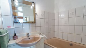 Ein Badezimmer mit Waschbecken, Spiegel und Badewanne.