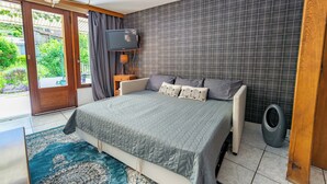 Ein Schlafzimmer mit Bett, Fernseher, Heizung und Blick ins Freie.