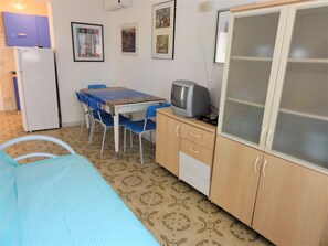A room with a bed, a table with chairs, a television, and a cabinet.