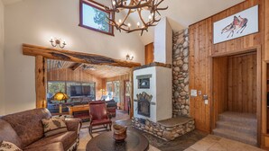 A cozy living room with a fireplace, wooden walls, and a stone accent wall. - The Moose’s Retreat - nestled in the trees in the Aspens. (Wilson)