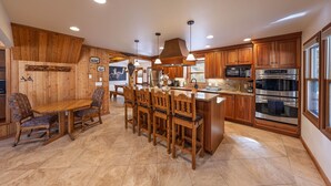 A kitchen with wooden cabinets, a central island, and modern appliances. - The Moose’s Retreat - nestled in the trees in the Aspens. (Wilson)