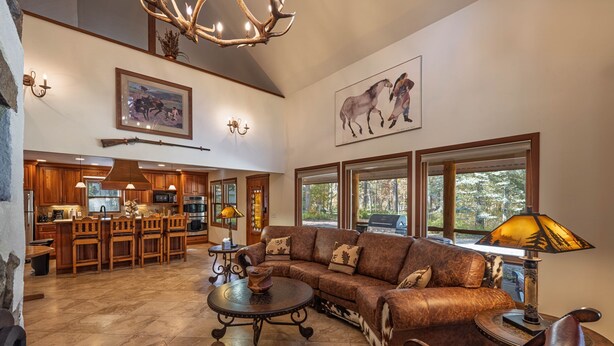 A spacious living area with a large sectional sofa, a dining table, and a kitchen in the background. - The Moose’s Retreat - nestled in the trees in the Aspens. (Wilson)