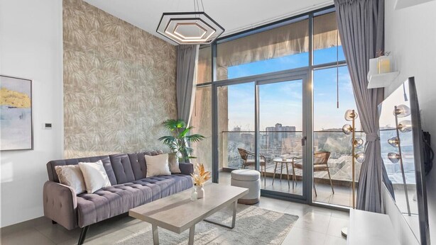 Ein modernes Wohnzimmer mit grauem Sofa, einem Couchtisch und einem großen Fenster mit Blick auf die Stadt.