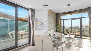 Ein modernes Hotelzimmer mit Essbereich, großen Fenstern und Blick auf die Stadt.