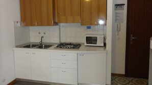 Uma cozinha com armários de madeira, micro-ondas, pia e fogão a gás.
