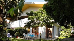 Ein kleines Haus mit Terrasse, umgeben von üppigem Grün und einem gepflegten Rasen.