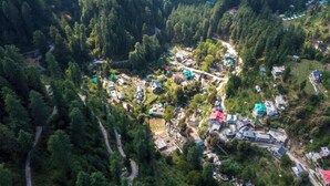 Vue aérienne d’une zone boisée parsemée de bâtiments, de routes et de clairières.
