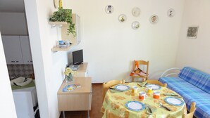 A compact living space with a dining area, a kitchenette, and a sofa.