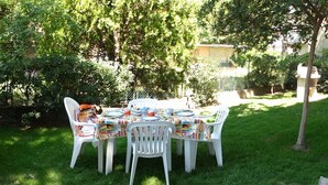 An outdoor dining area with a table set for four, surrounded by lush greenery and trees.