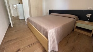 Un dormitorio con cama de madera, mesita de noche, escritorio y armario.