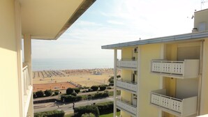 Ein Balkon mit Blick auf einen Strand und ein mehrstöckiges Gebäude mit Balkonen.