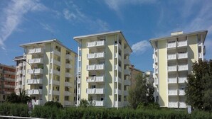 Drei mehrstöckige Wohngebäude mit Balkonen unter blauem Himmel.