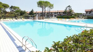A swimming pool with lounge chairs and a tiled deck. - Bright two-storey flat (Bibione)