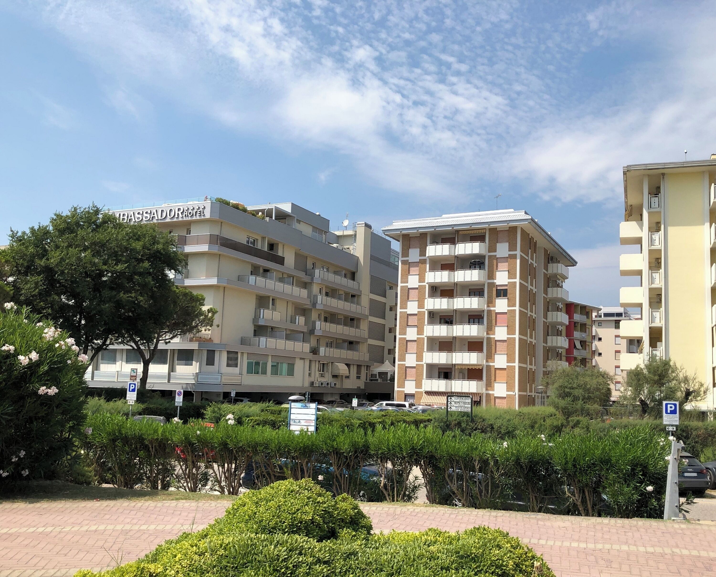 Un immeuble résidentiel à plusieurs étages, doté de balcons, avec un panneau indiquant un espace de stationnement et un arbre au premier plan.