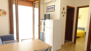 Une cuisine compacte équipée d’un réfrigérateur, d’une table à manger avec des chaises et d’une porte coulissante donnant sur une autre pièce.