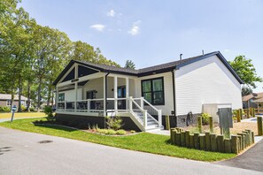 Ett enplanshus med en veranda, en trappa och en liten trädgård.