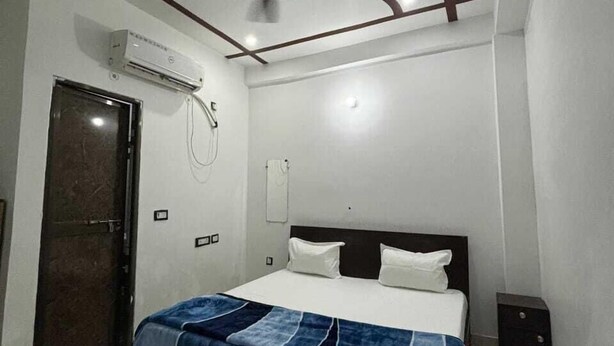 A bedroom with a bed, a ceiling fan, an air conditioning unit, and a door. - Radhe Ji Home Stay By Wishotel, Kharagpur, India (Faizabad)