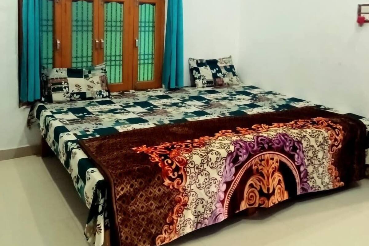 Un dormitorio con cama, cortinas, ventilador de techo y una ventana con rejas.