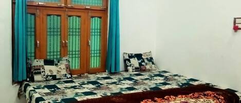 A bedroom with a bed, curtains, a ceiling fan, and a window with bars.