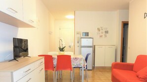 Een knus woongedeelte met een eethoek, een kitchenette en een rode bank.