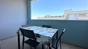 Un balcón con mesa y sillas, vista a edificios y cielo despejado.