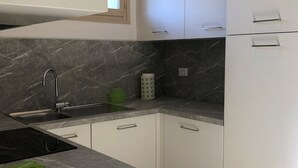 A kitchen with white cabinets, a marble countertop, and a sink.