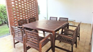 A wooden dining table with six chairs, a brick wall with a lattice design, and a tiled floor.