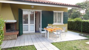 Un patio con una mesa y sillas, una chimenea de ladrillo y un ventanal corredero.