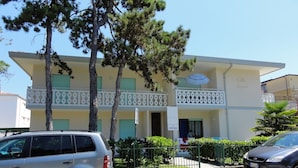 A two-story building with a balcony, a sign indicating 'LIVENZA', and a parked car in front. - Bright flat close to the spa (Bibione)