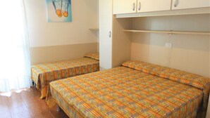 A room with two single beds, a painting on the wall, and a cabinet above the beds.