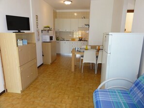 A compact kitchen with a dining area, a television, and a refrigerator.