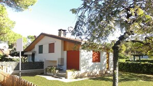 Une maison moderne à deux étages, avec une porte rouge, une antenne parabolique et une pelouse bien entretenue.