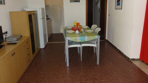 A compact kitchen with a dining table, chairs, and a refrigerator. - Semi-detached villa in a nice area (Bibione)
