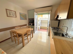 A compact kitchen with a dining table, chairs, and a sink. There is a microwave and a cabinet above the counter.