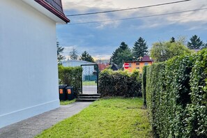 Zona residencial con un camino que lleva a una entrada con portón, rodeada de vegetación y viviendas.