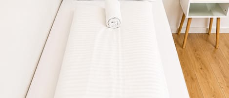 A single bed with a white mattress and a beige headboard.