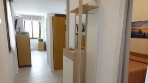 Ein Flur mit einem Holzschrank, einer Mikrowelle und einem kleinen Tisch mit einer Vase.