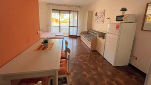 Una cuina pràctica amb zona de menjador, nevera, microones i una taula petita amb cadires.