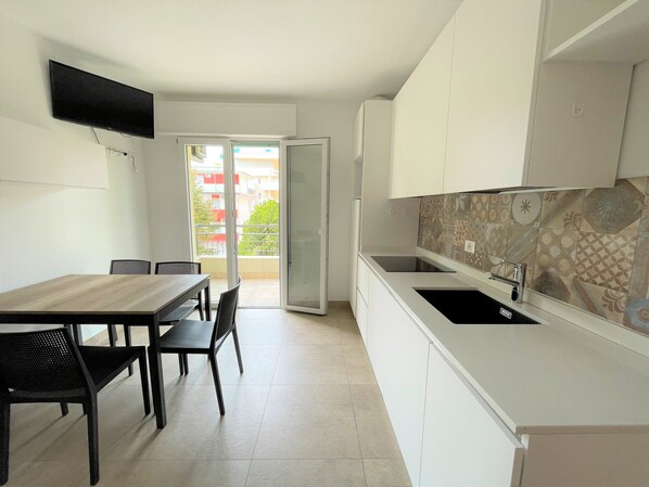 A modern kitchen with white cabinets, a black countertop, and a tiled backsplash.