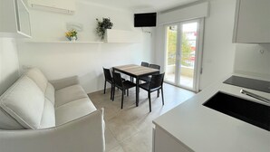 Eine moderne Küche mit Essbereich, einer Couch und einem an der Wand befestigten Fernseher.