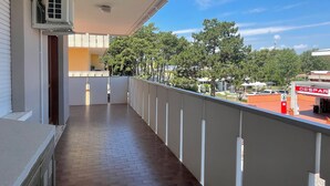 A balcony with a brick floor, white railing, and an air conditioning unit on the wall.