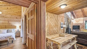 Een houten hut interieur met een bed, een eettafel en een bank.