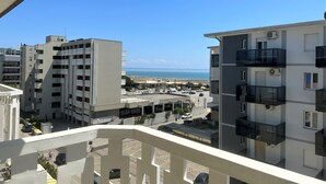 Vista de un complejo de edificios costeros con balcones que dan a una playa y al mar.