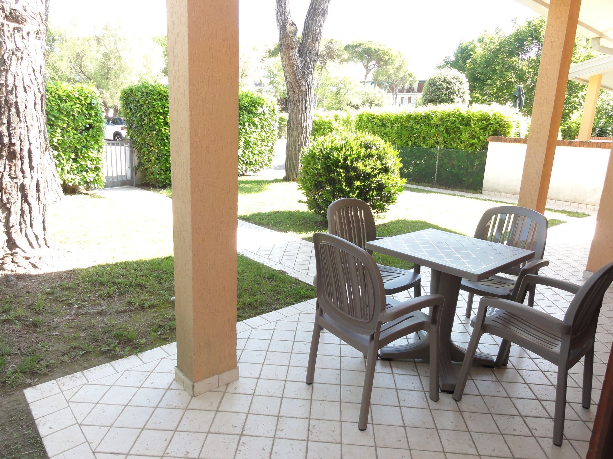 Un patio al aire libre con piso de baldosas, una mesa y cuatro sillas.