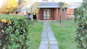 Un immobile residenziale con un vialetto lastricato che conduce a una porta in legno, circondato da siepi e alberi curati.