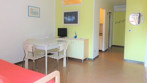 Una habitación con una mesa de comedor, sillas, un televisor y una cama.